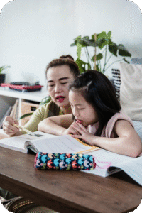 Parent guiding a child with writing homework at home